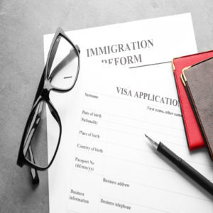 Passports, glasses and visa application form on table. Immigration visa reform