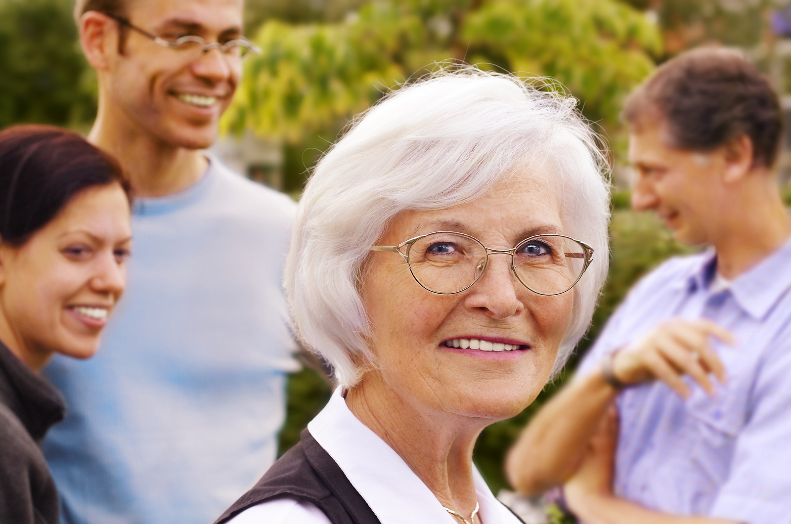 Senior woman smiling in front of three young people, outdoor