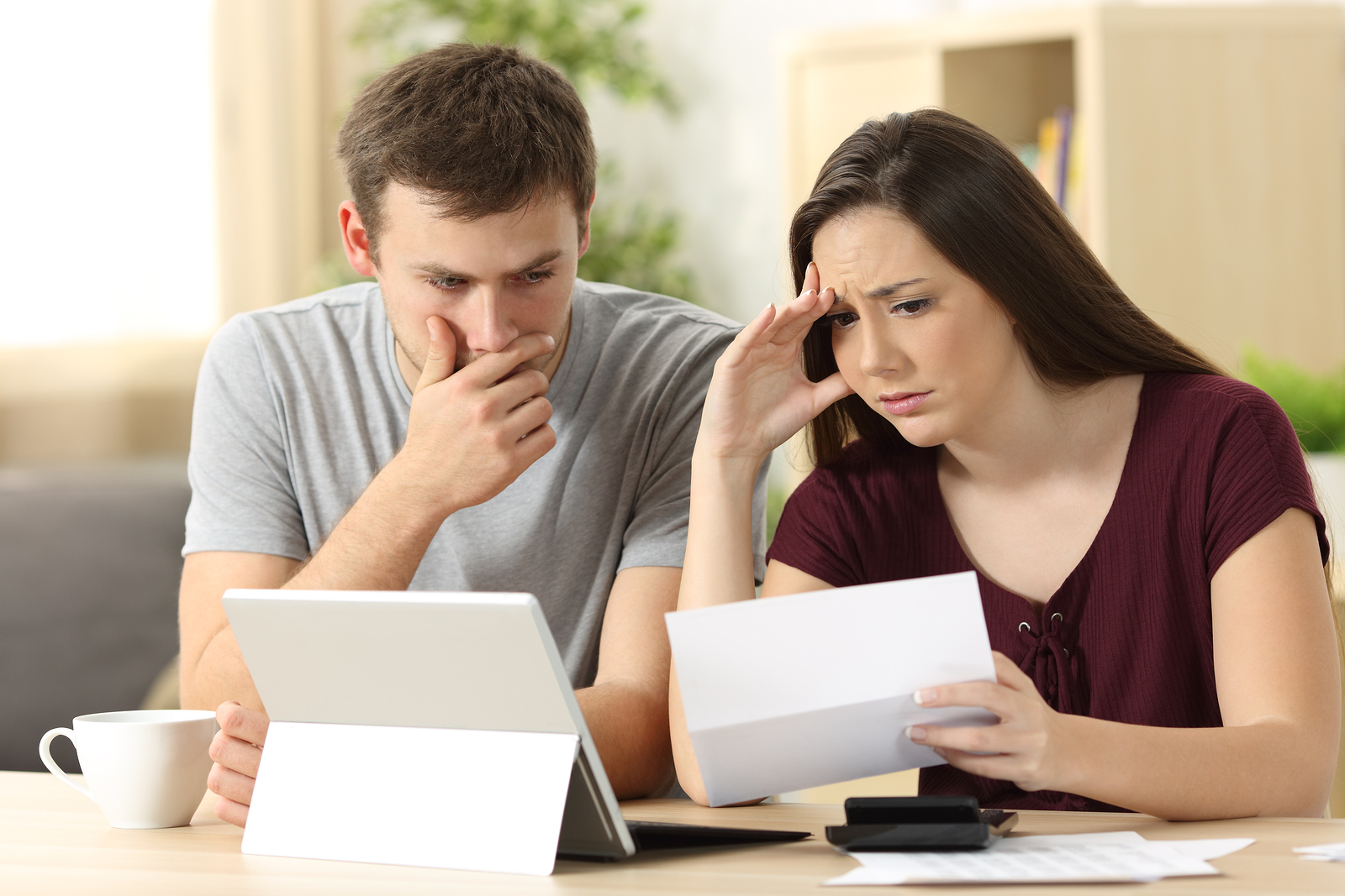 Worried couple reading together a letter sitting in a desk at home
