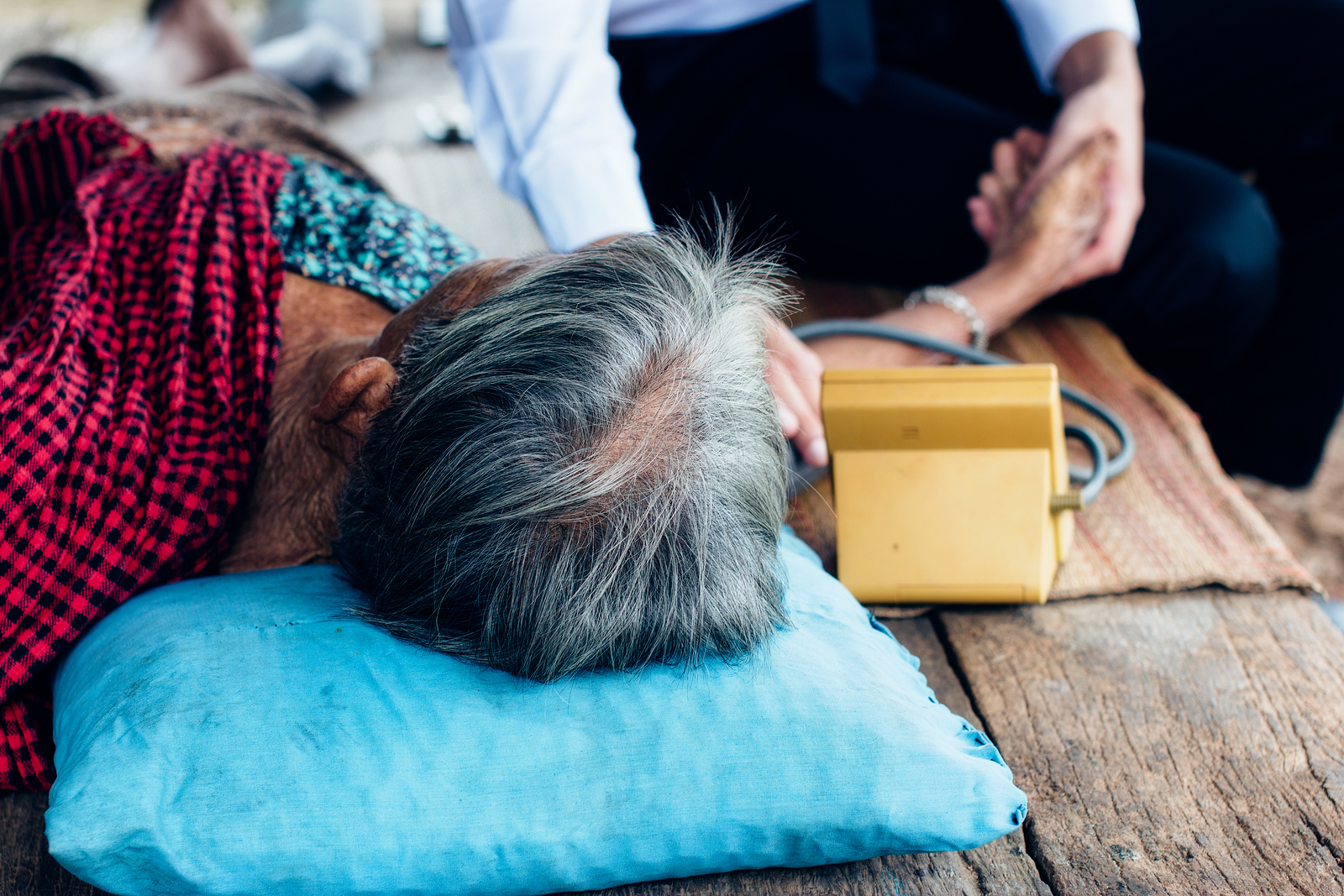 Male Doctor listening heart beat and breathing of Elderly Woman with Stethoscope with First Aid Medical Box.Community Health and Development Hospital In Remote Areas Development Fund Concept.