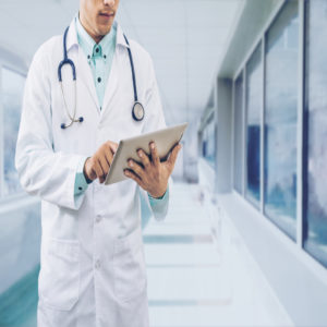 Male doctor working on computer tablet wearing doctors uniform in a hospital or doctors office. Concept of medical data analysis by doctor medical technology and doctors data.